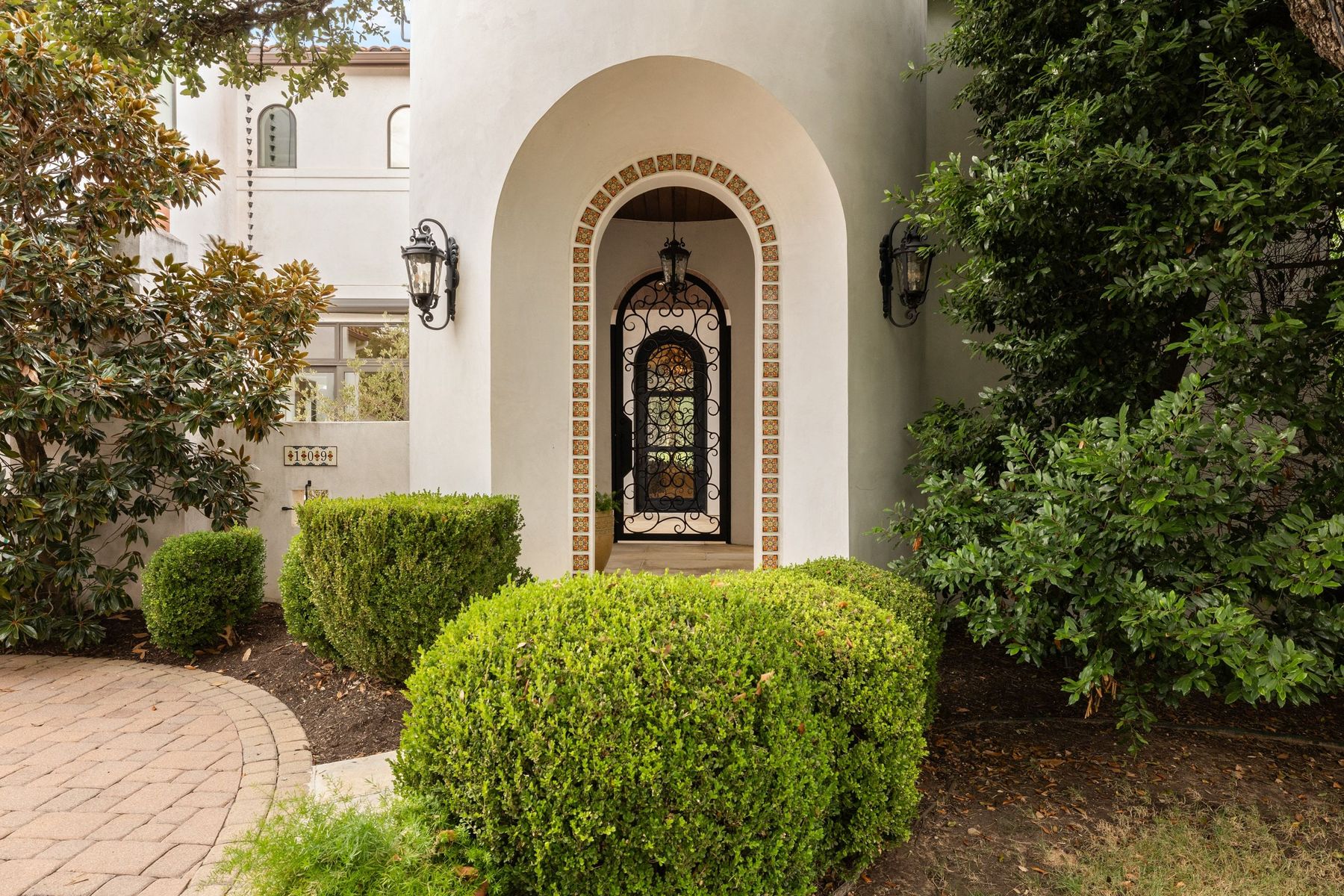 Arched front entry with iron door and clipped boxwoods
